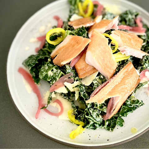 Smoked Trout kale caesar salad on white plate