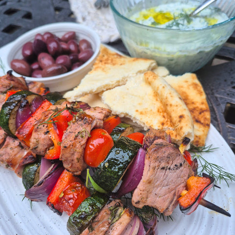 wild boar tenderloin souvlaki on a plate with pita and olives